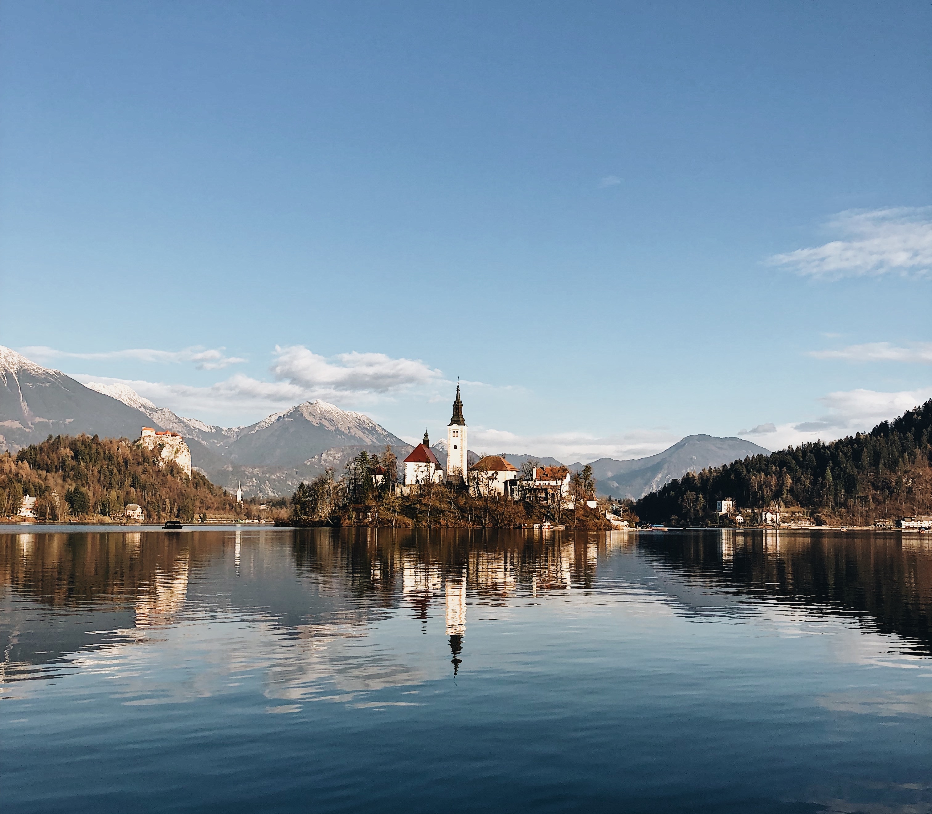 ancient castle surrounded by mountainous scenery reflecting lake