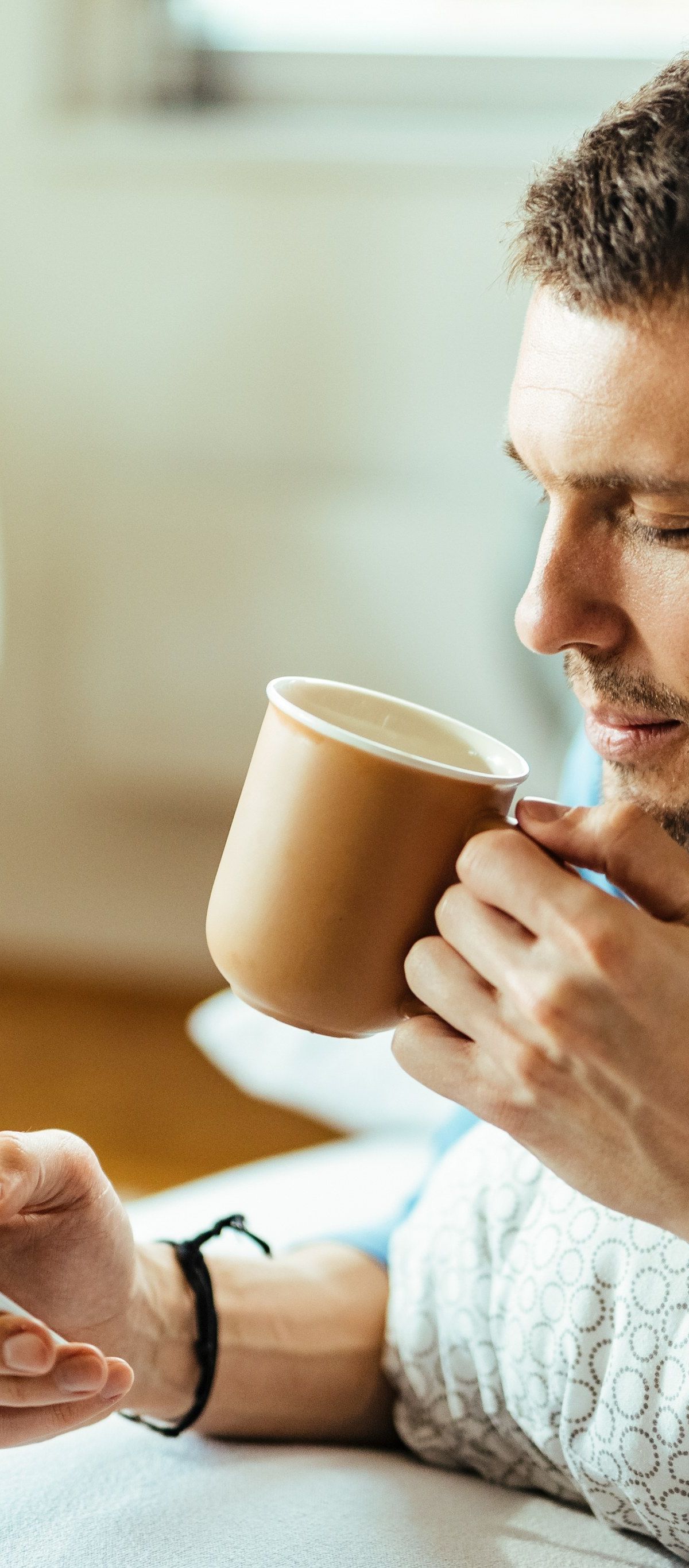 Mladenič s telefonom in kavo v postelji (Freepik)